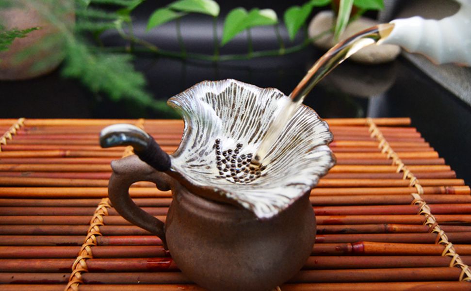 粗瓷茶器：定瓷銀杏葉茶漏擺放在茶臺(tái)上